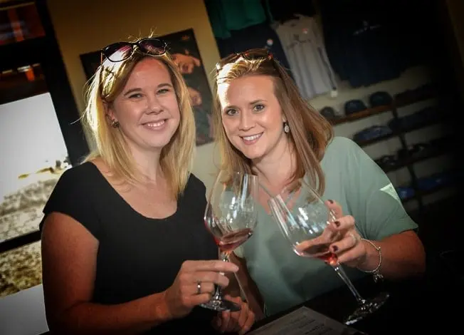 Two women holding wine glasses in front of entrance